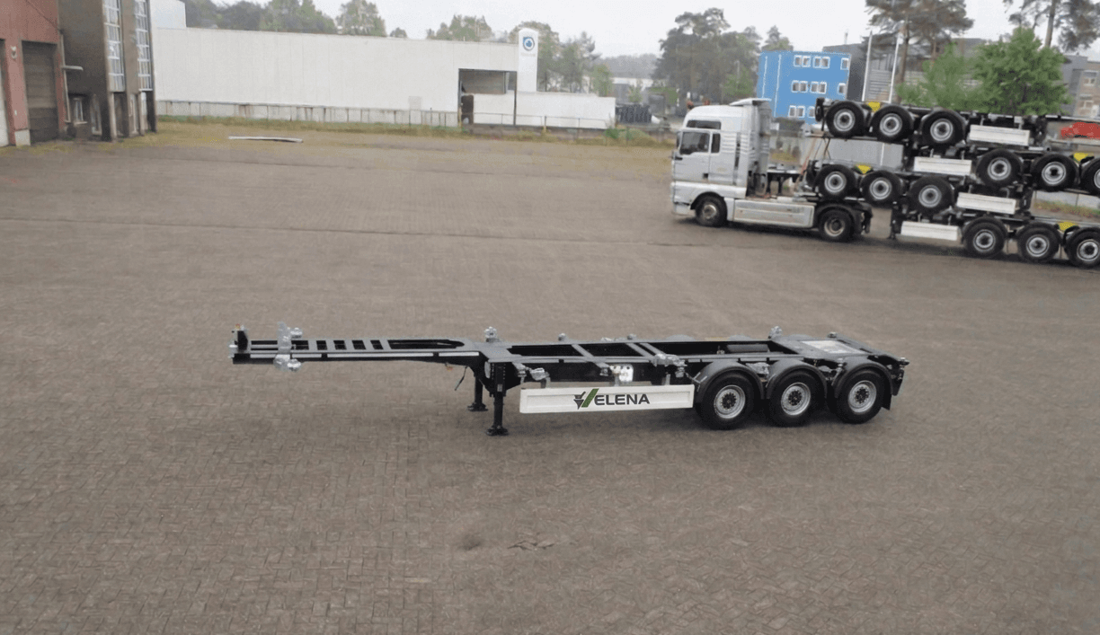 Black three-axle container chassis trailer with white Elena branding parked on a paved transport lot.